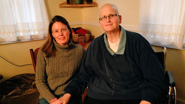 a woman and older man holding hands and sitting in room